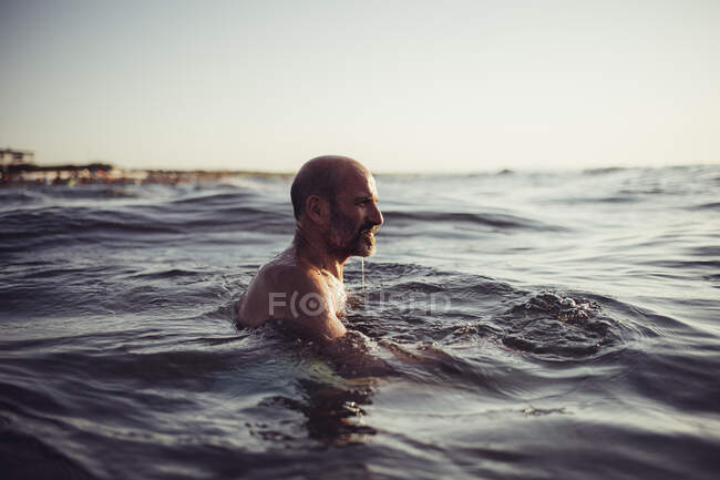 Senior man swimming in sea during sunset — Stock Photo