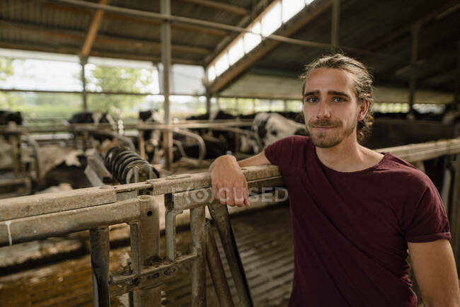 Retrato de um jovem agricultor em casa de vacas em uma fazenda — Fotografia de Stock