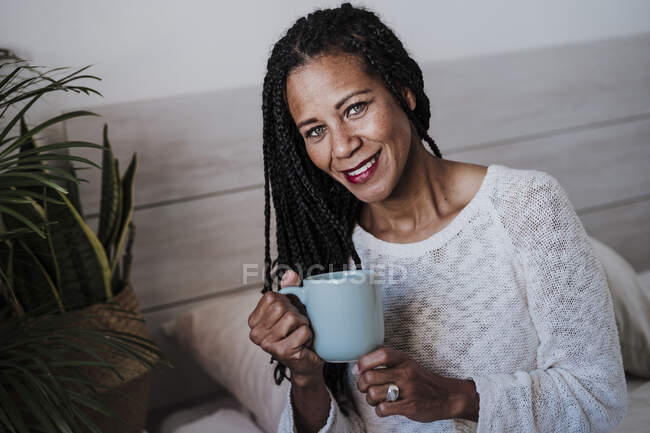 Sorrindo mulher madura bebendo café enquanto sentado em casa — Fotografia de Stock