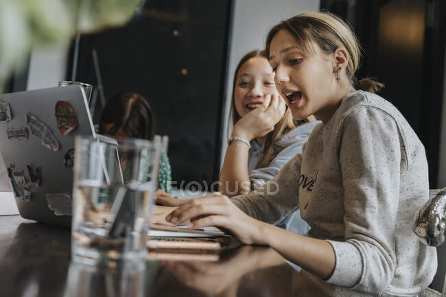 Adolescentes que estudian y aprenden desde casa, usando computadoras portátiles - foto de stock