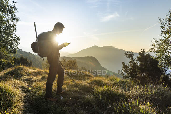 Homem silhueta usando telefone celular enquanto estava em pé na montanha contra o céu, Orobie, Lecco, Itália — Fotografia de Stock