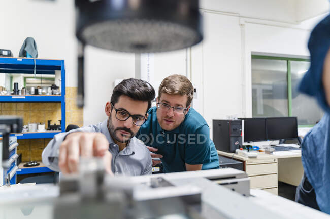 Businessman and male colleague examining surveyor machine in manufacturing factory — Stock Photo