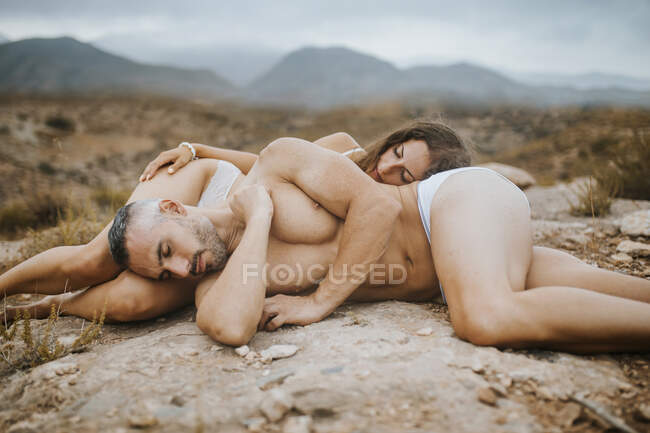 Чоловік і жінка лежачі в полі під час заходу сонця. — стокове фото