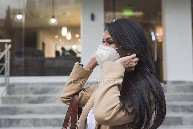 Femme portant un masque protecteur debout par des marches à l'extérieur du bâtiment pendant la COVID-19 — Photo de stock
