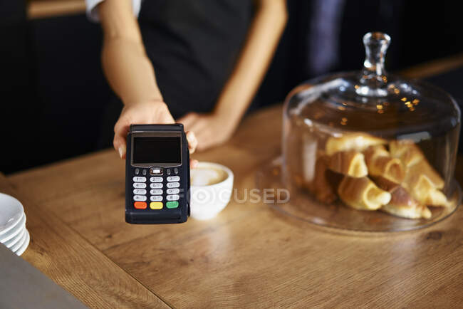 Midsection of waitress with credit card reader at cafe — Stock Photo