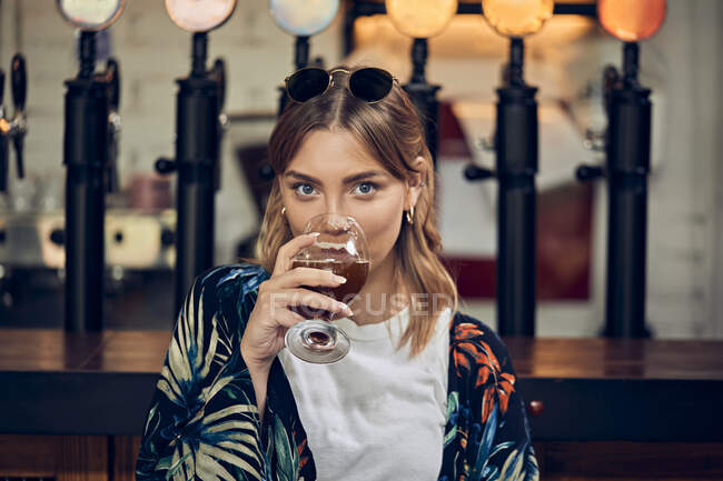 Retrato de una mujer sonriente en un pub tomando una cerveza - foto de stock