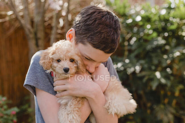 Junge umarmt Welpe im Hinterhof — Stockfoto