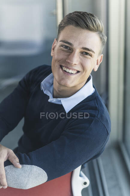 Зблизька усміхнений вродливий бізнесмен, що сидить в офісі. — стокове фото