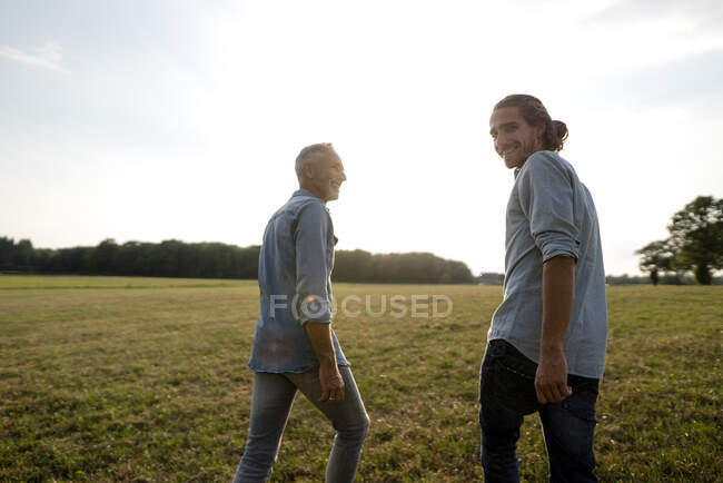 Feliz padre e hijo adulto caminando en un prado en el campo — Vista  trasera, Vida sencilla - Stock Photo | #479923436