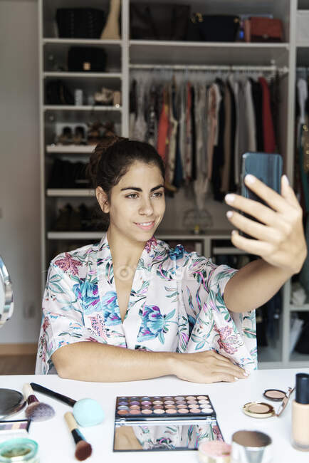 Молодая женщина делает селфи на смартфоне, сидя дома — стоковое фото