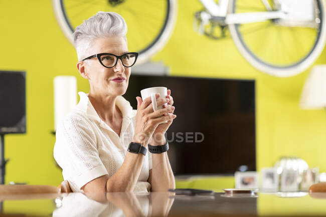 Lächelnde Seniorin, die zu Hause Kaffee trinkt — Stockfoto