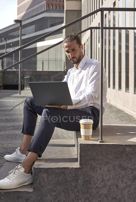 Uomo d'affari che lavora sul computer portatile mentre seduto sulle scale — Foto stock