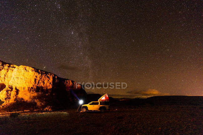 Auto fuoristrada nel campo illuminato del deserto di notte — Foto stock