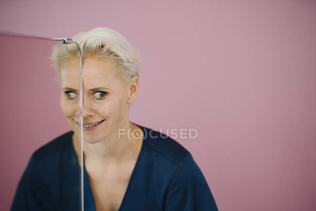 Gros plan d'une femme d'affaires souriante faisant visage par verre sur fond violet — Photo de stock