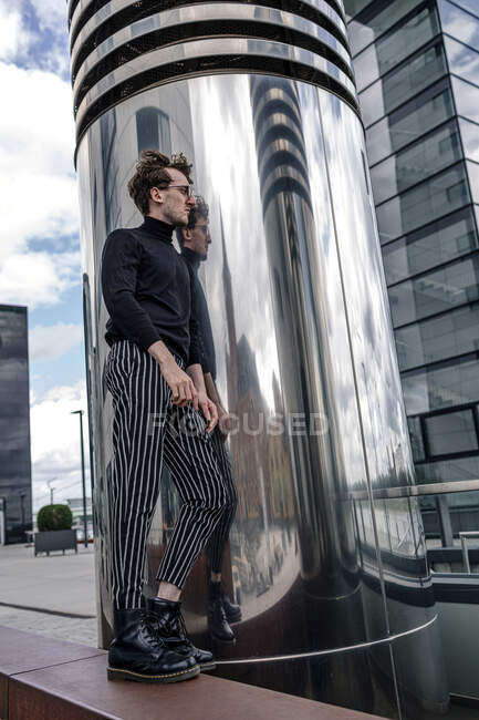 Вдумчивый молодой человек, стоящий у современной колонны в городе — стоковое фото