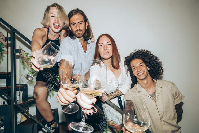 Amici con gli occhiali da vino sulle scale a casa durante la festa — Foto stock