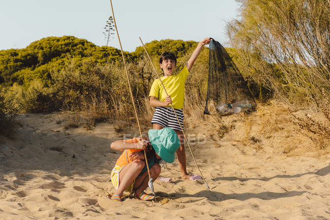 Cheerful friends cleaning beach — Stock Photo