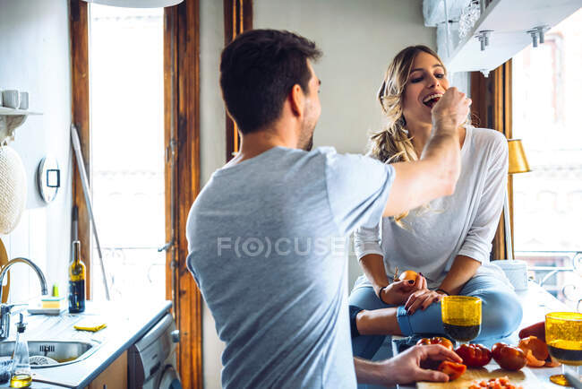 Giovane uomo preparare il cibo e l'alimentazione fidanzata in cucina a casa — Foto stock