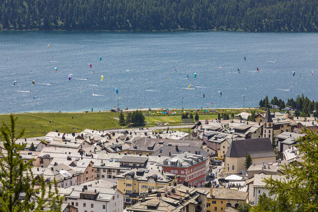 Switzerland, Canton of Grisons, Silvaplana, Lakeshore town in summer with kite surfers in background — Stock Photo