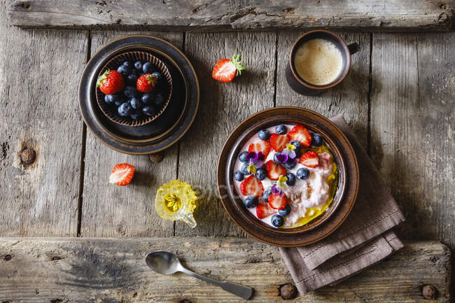 Tasse de café et assiette de quark aux fraises, bleuets et fleurs comestibles — Photo de stock