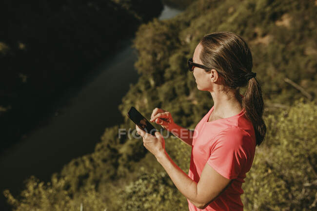 Mulher usando telefone celular em pé na montanha em Sierra De Hornachuelos, Córdoba, Espanha — Fotografia de Stock