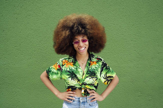 Sorridente giovane donna davanti al muro verde — Foto stock