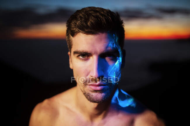 Handsome young man with blue neon color on face — Stock Photo