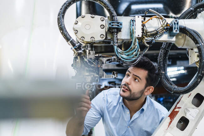 Мужчина-предприниматель, концентрирующийся при анализе деталей машин на заводе — стоковое фото