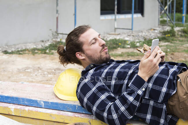 Роботодавці, лежачи на дереві, користуються смарт - телефоном. — стокове фото