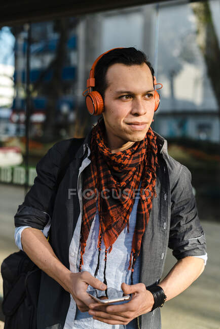 Чоловік дивиться геть, слухаючи музику через навушники — стокове фото