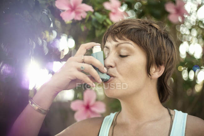 Mujer joven respirando a través del inhalador de asma - foto de stock