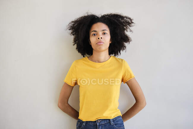 Junge Studentin steht mit den Händen hinter Kopf gegen Wand — Stockfoto