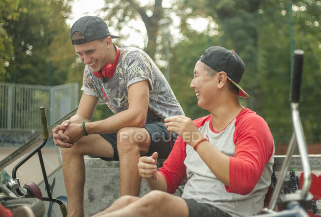 Jovens amigos alegres sentados no parque de skate — Fotografia de Stock