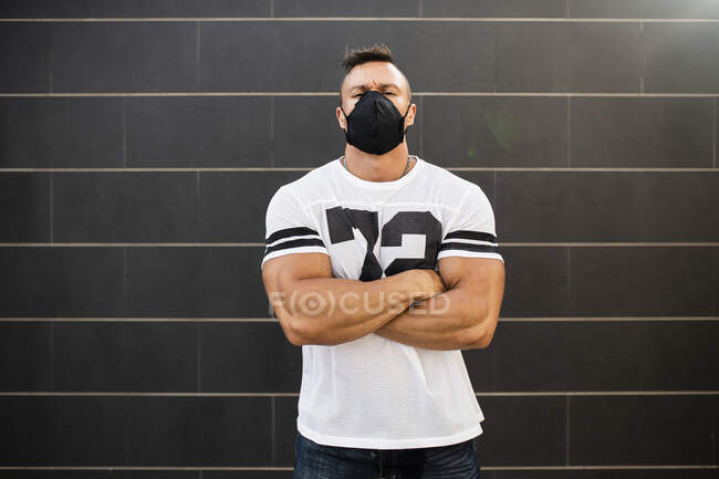 Macho jeune homme portant un masque facial debout contre le mur — Photo de stock