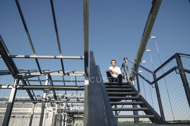 Scienziato seduto sulle scale sotto il cielo blu — Foto stock