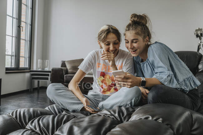 Fröhliche Freunde mit Smartphone beim Entspannen auf der heimischen Couch — Stockfoto