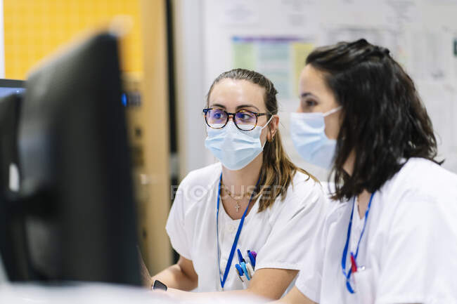 Close-up of female doctors wearing masks using computers in hospital — Stock Photo