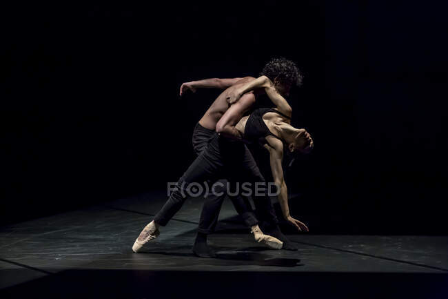 Мужчина и женщина танцуют современный балет на черной сцене — стоковое фото