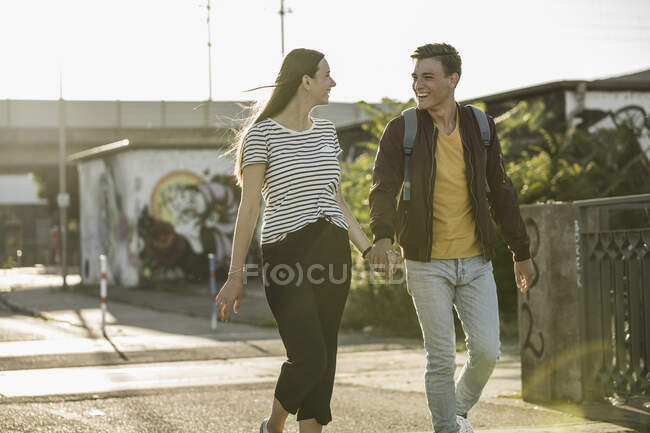 Happy young couple holding hands while walking on street — Stock Photo