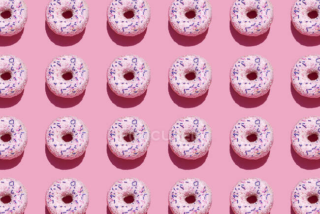 Patrón de rosquillas dulces sobre fondo rosa - foto de stock