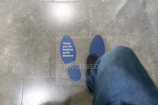 Frau tritt auf Fußbodenaufkleber mit der Aufschrift 