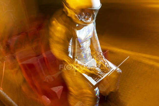 Astronauta masculino usando portátil mientras está sentado al aire libre - foto de stock