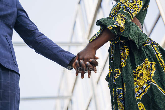 Молода жінка в традиційному одязі, тримаючи за руку чоловіка, стоячи в будівлі. — стокове фото