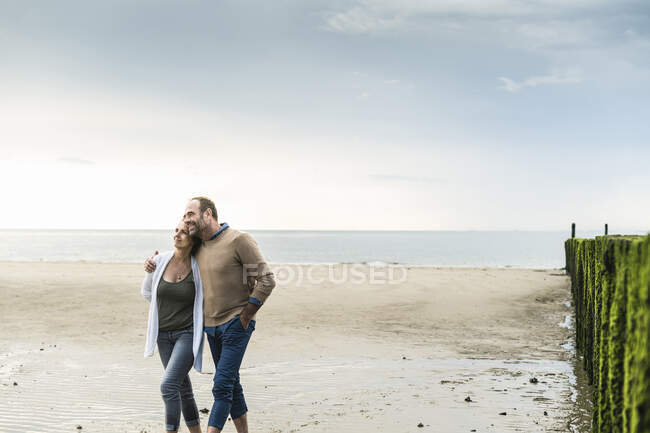 Loving mature couple walking at beach against sea during sunset — Foto stock