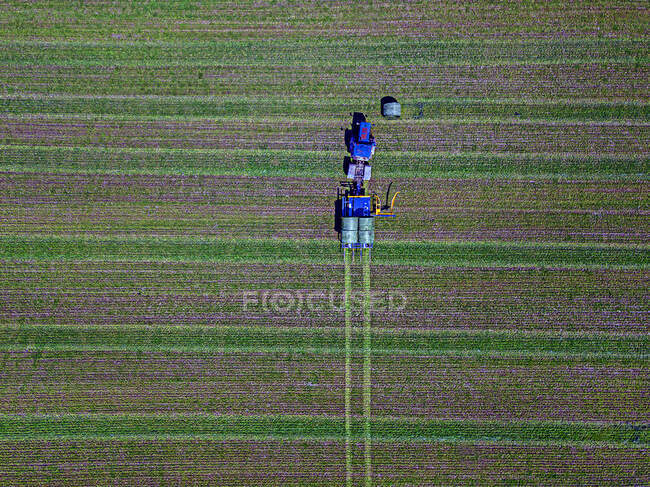 Воздушный обзор трактора, собирающего тюки сена в поле — стоковое фото
