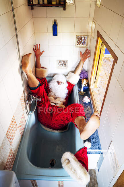 Uomo che indossa il costume di Babbo Natale che cade nella vasca da bagno a casa — Foto stock