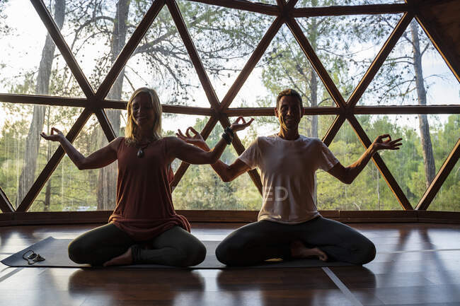 Donna e uomo sorridente che praticano yoga contro finestra nella spa della salute — Foto stock