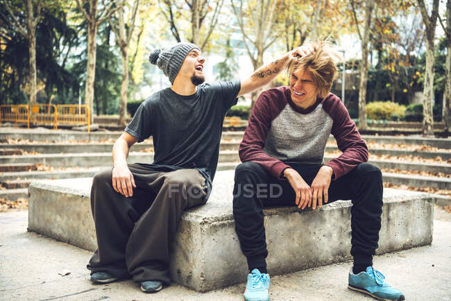 Lächelnde männlich aussehende Freundin sitzt im öffentlichen Park — Stockfoto
