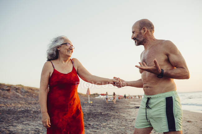Coppia anziana che si tiene per mano mentre si trova in spiaggia — Foto stock
