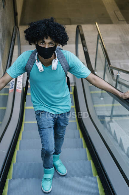 Mann mit Schutzmaske steht auf Rolltreppe in der Stadt — Stockfoto
